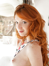 Michelle with curly orange hair naked on the chair